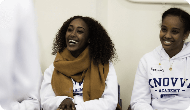 Two students involved in the student leadership program smile and interact with each other.